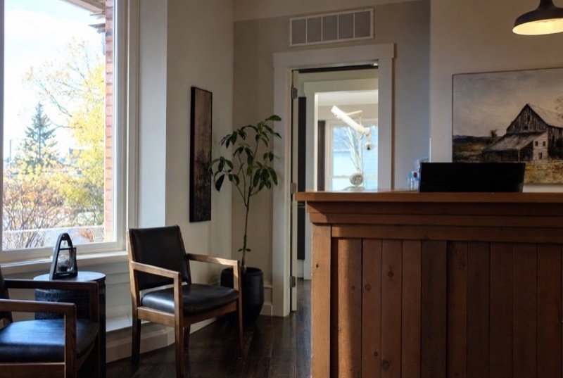 Sunny front desk of a dental clinic, its counter in warm wood beside a big window